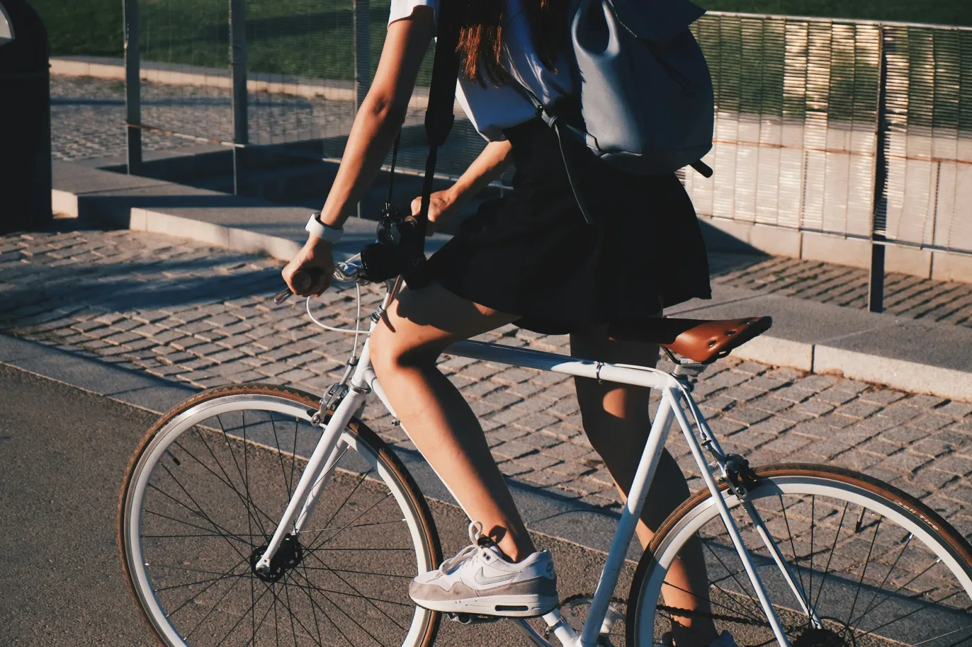 Jonge vrouw op een witte fiets in laag zonlicht, uitgesneden vanaf de schouders
